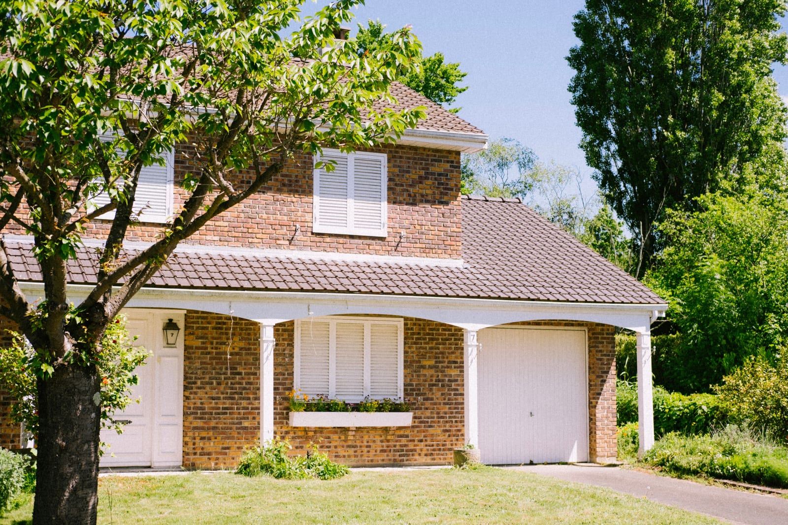 A two-story brick house with a garden out front.